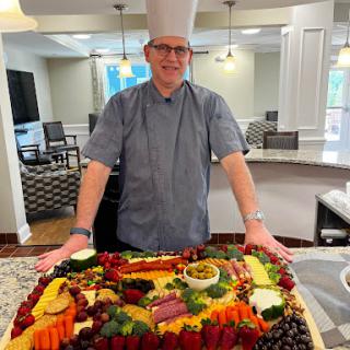 A talented chef showcasing a beautifully arranged fruit and cheese platter in a modern kitchen.