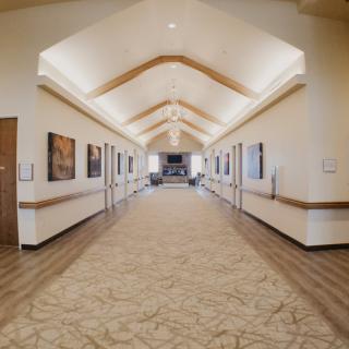 A well-lit hallway featuring art on the walls and wooden flooring.