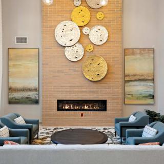 A modern living room with a cozy seating area and decorative wall clocks above a fireplace.