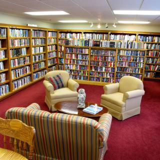 A cozy library with comfortable seating surrounded by bookshelves filled with books.