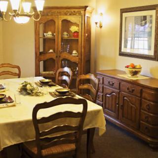 A cozy dining room with a traditional wooden dining table set, illuminated by a chandelier.