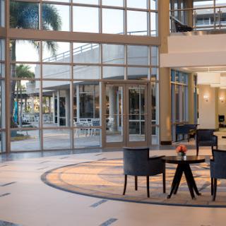 A spacious and modern lobby featuring elegant furniture and large glass windows allowing natural light to fill the space.