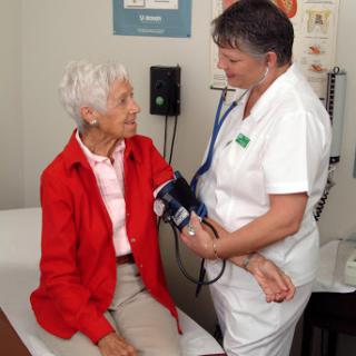A nurse takes the blood pressure of an elderly patient during a medical examination.