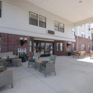 Outdoor seating area in front of a brick building with entrance.
