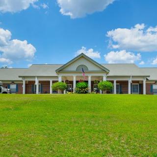 A large building with a porch under a blue sky with clouds.