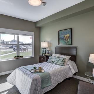 A cozy bedroom with a large window, modern decor, and neutral color palette.