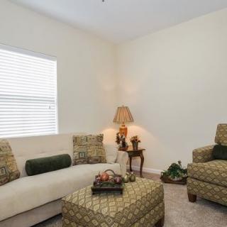 A cozy living room with a sofa, an armchair, and a lamp beside the window.