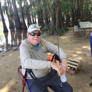 A person enjoying a peaceful day fishing by the river in a forested area.