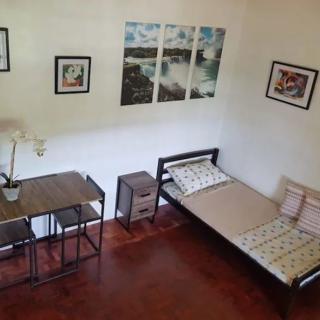 A minimalist bedroom with a single bed, desk, and wall art.