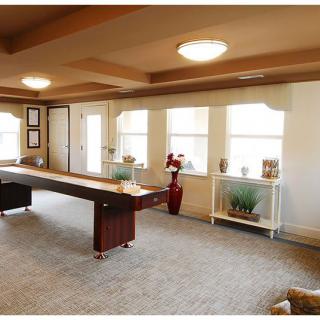 A spacious room with a long table, multiple windows, and warm lighting.