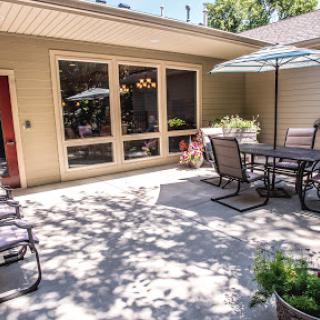 A cozy outdoor patio area with a table, chairs, and an umbrella, perfect for relaxing in the shade.