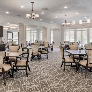 A well-lit dining room with elegant furniture and large windows.
