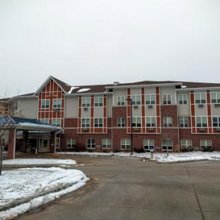 A residential building with a welcoming entrance, surrounded by snow on a cloudy winter day.