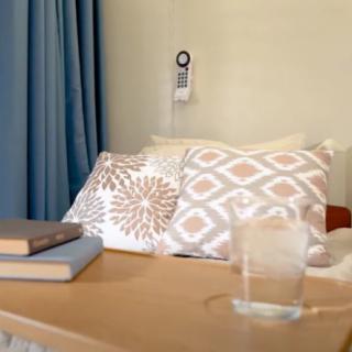 A cozy bedroom setup featuring patterned pillows, a stack of books, and a glass of water on a nightstand.