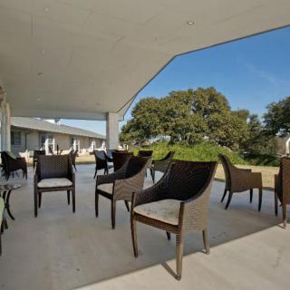 A modern outdoor patio with chairs overlooking lush greenery on a sunny day.