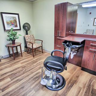 A modern hair salon interior with a barber chair, stylish cabinets, and decor elements.