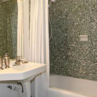 A bathroom with mosaic tile walls, a bathtub, and a white sink.