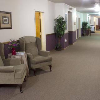 A quiet hallway with upholstered chairs and potted plants.