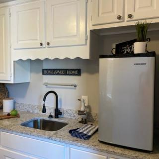 A compact kitchen area with a sink, countertop, mini fridge, and cabinets.