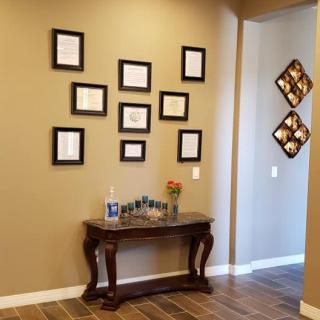 A hallway featuring a console table with decorative items and an arrangement of picture frames on the wall.