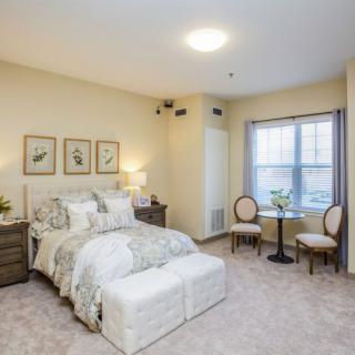 A spacious and cozy bedroom featuring neutral tones, elegant decor, and ample natural light.