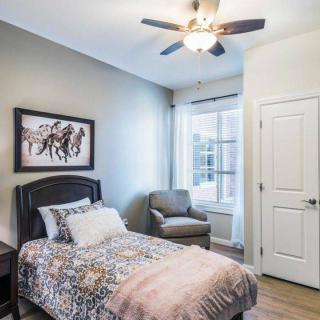 A cozy bedroom with a single bed, armchair, and ceiling fan.
