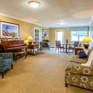 A cozy living room with a piano, seating area, and dining space, illuminated by warm lighting.