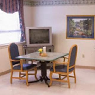 A cozy dining area with a table, two chairs, a television, and a painting on the wall.