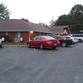 A red car parked in a residential parking lot during the evening.