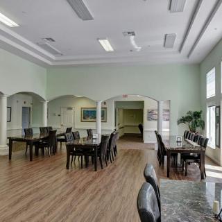A spacious dining area with multiple tables and chairs, featuring large windows that allow natural light to fill the room.