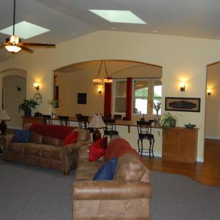 A spacious and well-lit living room featuring comfortable sofas, a ceiling fan, and elegant decor.