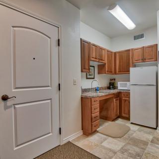 A compact apartment kitchen with wooden cabinets, a refrigerator, and essential appliances.