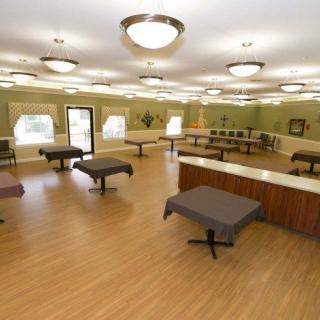 An empty room with tables, bright lighting, and wooden flooring.