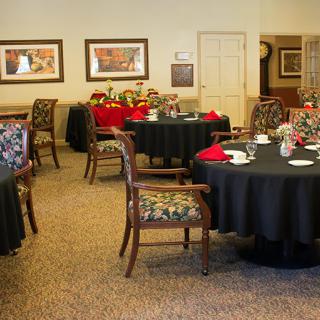 A cozy dining area with elegantly set tables and upholstered chairs.