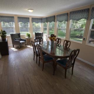 A bright dining area with a wooden table and chairs, surrounded by large windows.