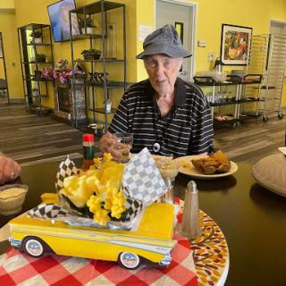 An elderly individual enjoying a meal in a vibrant dining area, celebrating with festive decorations.