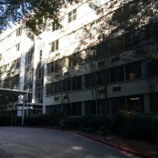 A hospital building surrounded by trees and a driveway.