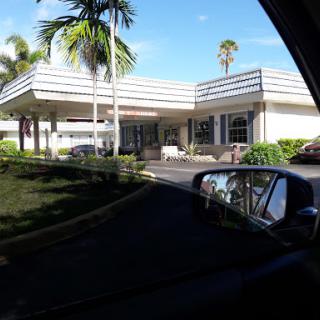 A view of a modern commercial building surrounded by palm trees on a sunny day.