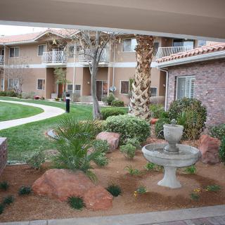 A well-maintained courtyard with a fountain and lush landscaping at an apartment complex.