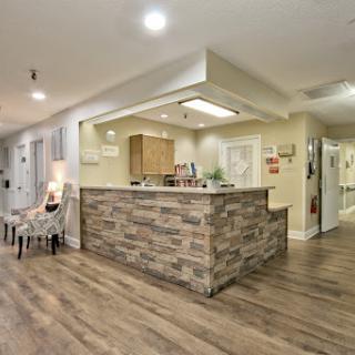A modern reception area featuring a stylish stone-front desk and warm wooden flooring.