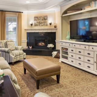 A cozy living room with a fireplace, armchairs, and a television set.