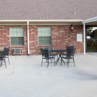 An outdoor patio area with metal tables and chairs in front of a brick building.