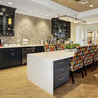 A modern kitchen with a large island, colorful bar stools, and sleek cabinetry.