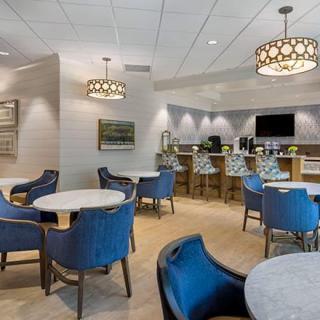 A modern lounge with blue upholstered chairs, round tables, and stylish pendant lighting.