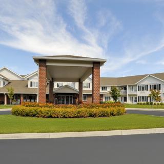 A modern residential building with a landscaped entrance and driveway.