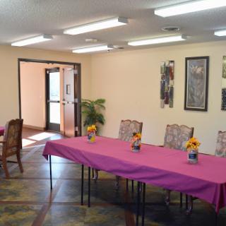 A well-lit meeting room set up for an event with a pink tablecloth and flower centerpieces.