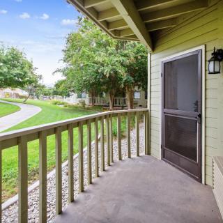 A cozy patio with a wooden railing overlooking a lush, green yard.