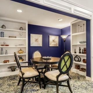 A cozy dining area with elegant furniture and built-in bookshelves against a striking blue accent wall.