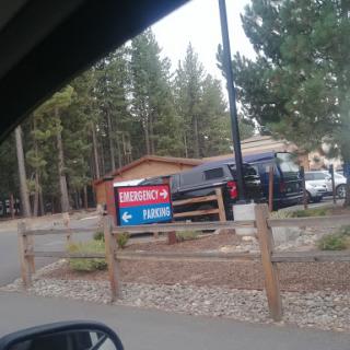 A view of a parking area with signage in a wooded setting.