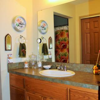 A cozy bathroom with a sink and mirror, colorful decor, and a shower curtain.